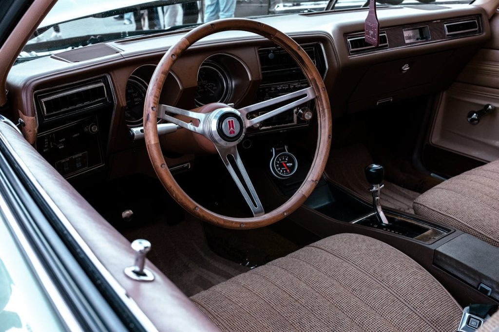 Explore the detailed elegance of a vintage car interior featuring a wooden steering wheel and classic design.