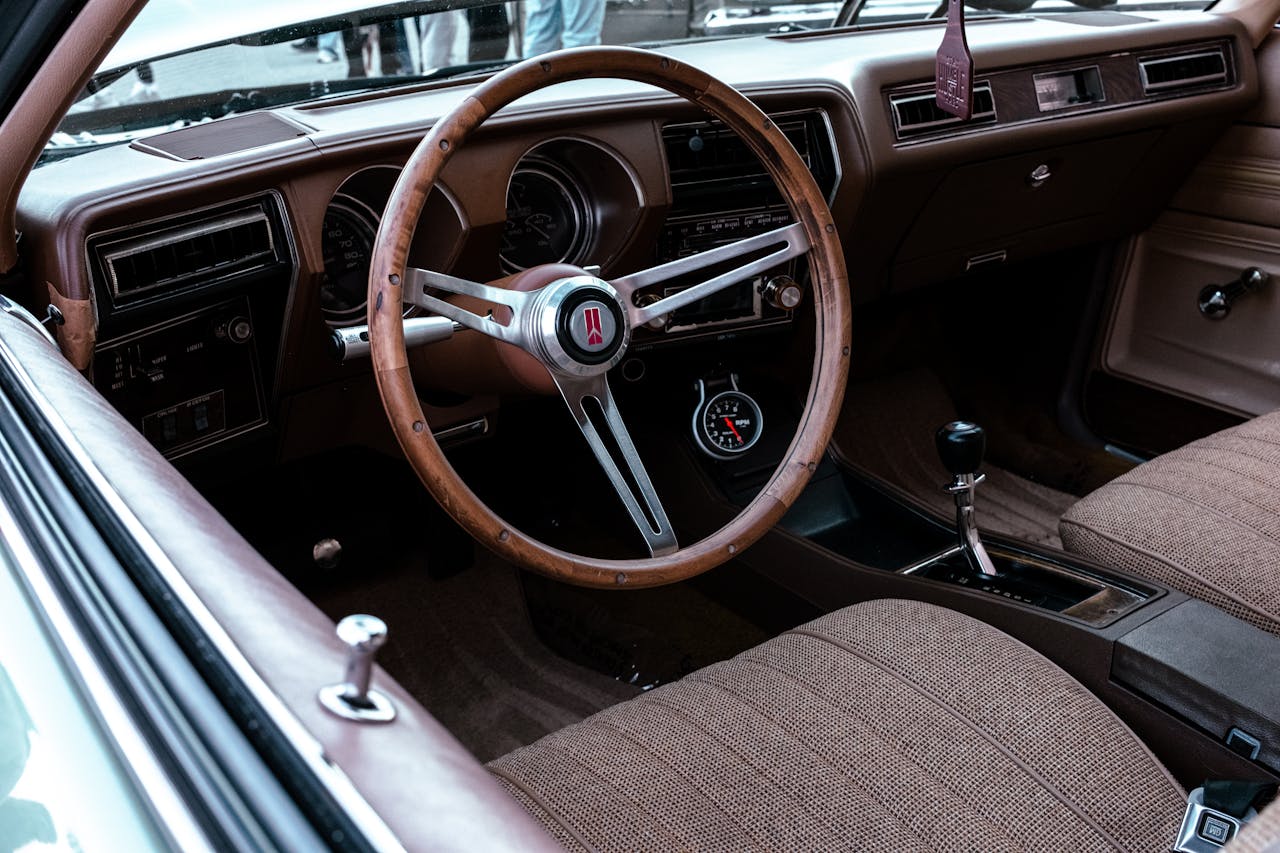 Explore the detailed elegance of a vintage car interior featuring a wooden steering wheel and classic design.